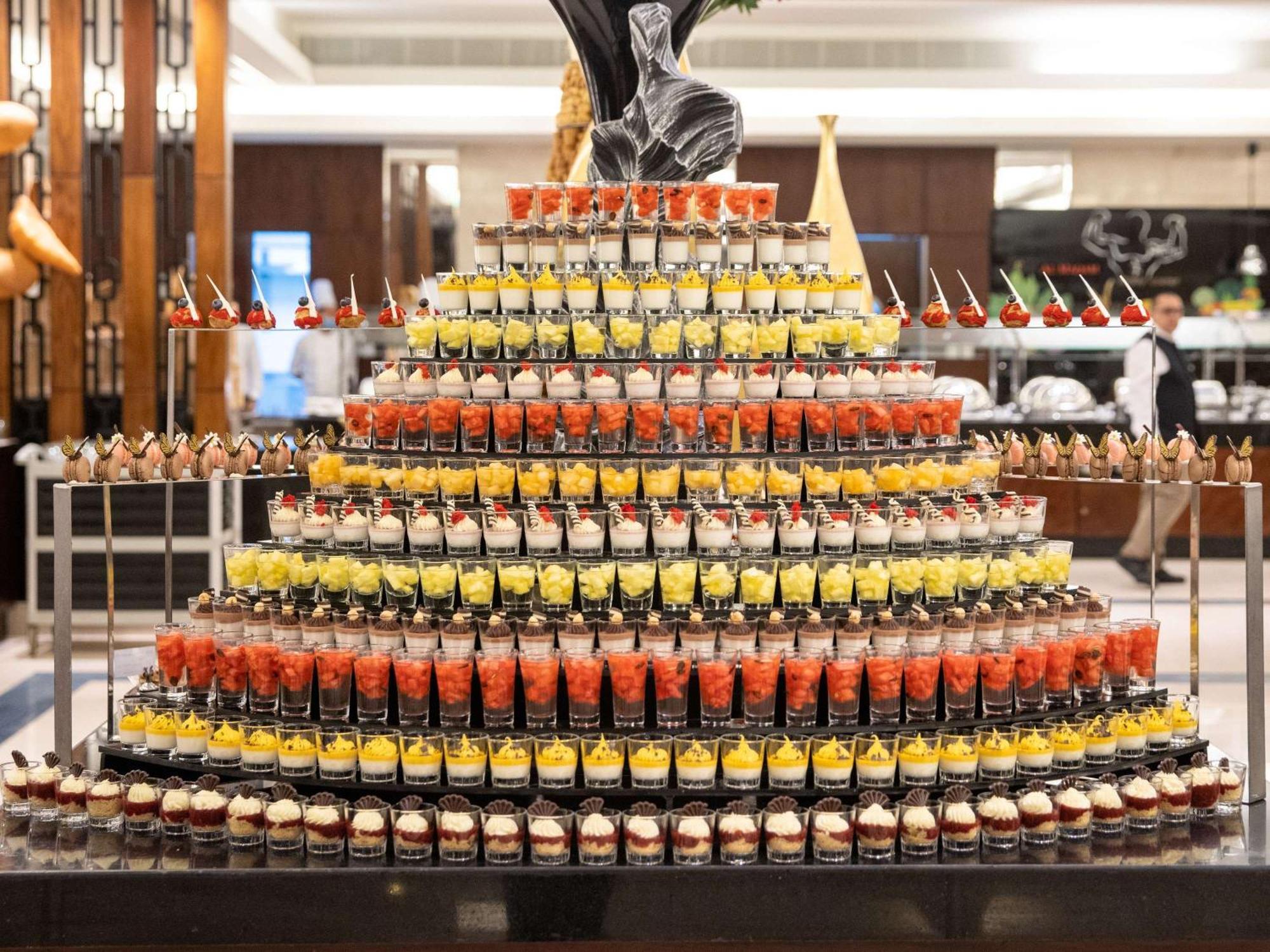 Swissotel Al Maqam Makkah Meca Exterior foto The photo displays an impressive dessert display arranged in a pyramid shape. Each layer consists of numerous small dessert cups filled with different colorful treats. The top layer features a decorative element, possibly a statue or a centerpiece, w